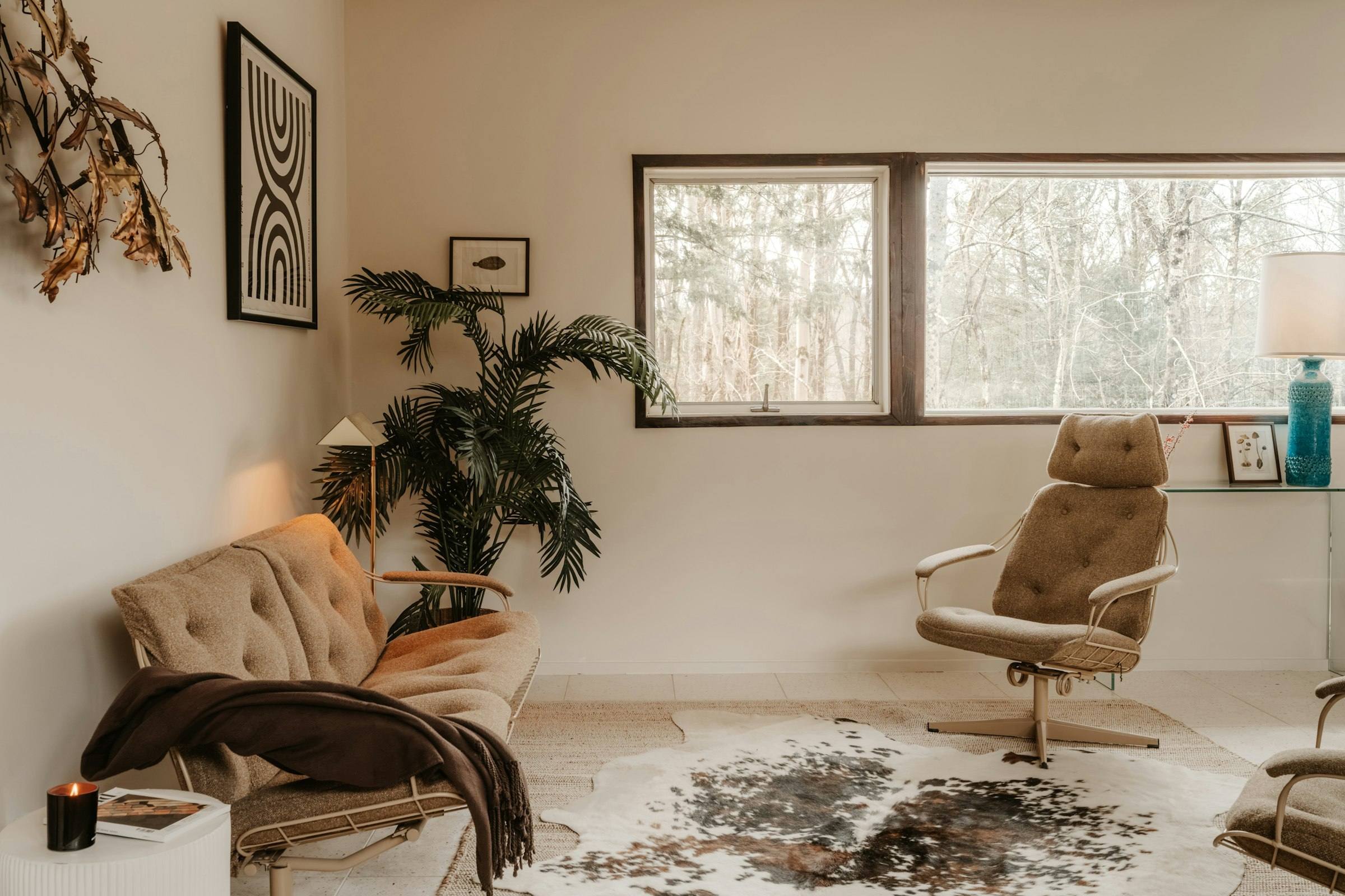 A calm, sunlit sitting room with two armchairs, a soft rug and potted plants